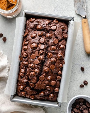 A loaf of chocolate pumpkin bread with chocolate chips in a baking loaf tray.