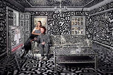 Sam Cox and his wife sitting on a doodled couch in a completely doodled living room.