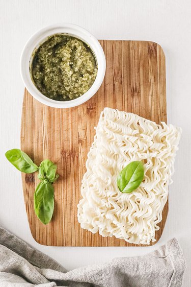 Pesto, ramen, and basil on a wooden cutting board