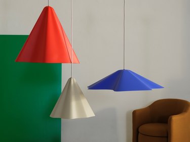 Three hanging light fixtures in red, beige, and blue that look like hanging pieces of cloth.