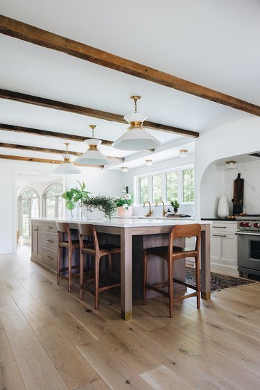 white kitchen with brown exposed beams and island