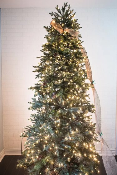A burlap ribbon is continuing to be wrapped around a Christmas tree