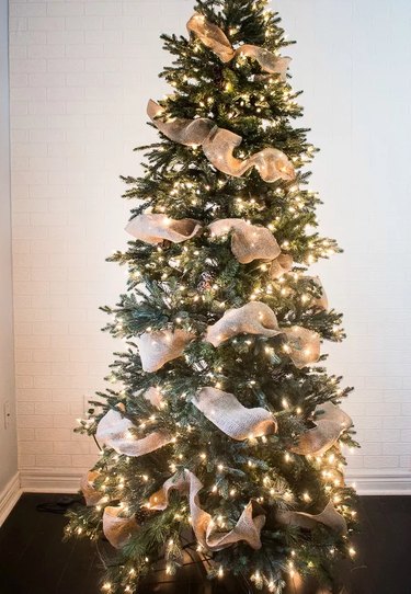 A Christmas tree with burlap ribbon from top to bottom