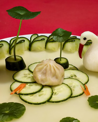 fly by jing dumpling on plate with cucumber and swan
