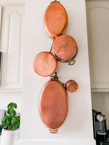 Hanging copper pots on white kitchen wall.