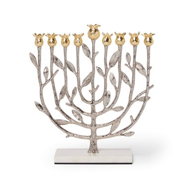 A silver menorah, showcasing the divine tree, has silver leaves and golden pomegranates at the top.