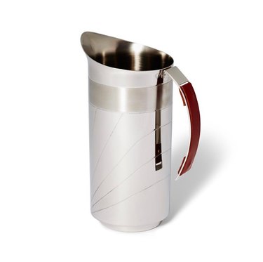A stainless steel pitcher, with a brown leather handle with etches on the side. The pitcher is meant to mimic Italian armor,