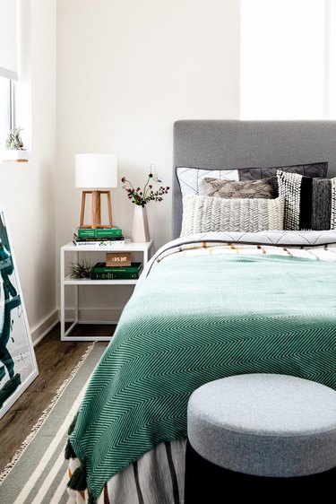 cool gray bedroom with gray headboard, white linen and green blanket