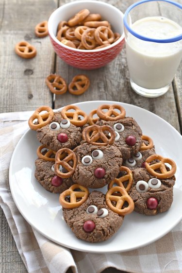 Reindeer shaped cookies with pretzels and a glass of milk on a table