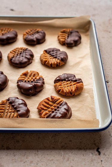 Peanut butter cookies dipped in chocolate on a cookie sheet
