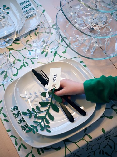 table with dishes and green and white table runner with person's hand