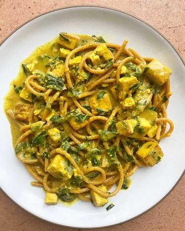 Curry noodles on a white plate by Chitra Agrawal