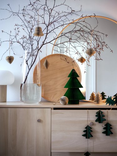 sideboard with mirror and branches and green tree decor