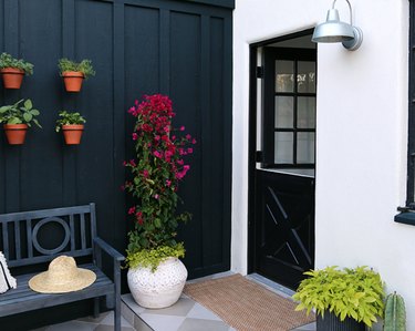 Black dutch door, black paneled fence, potted plants, bench.