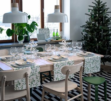 wood table with green and white decor and christmas tree nearby