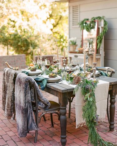 outdoor table with cedar garland and fur blankets on chairs
