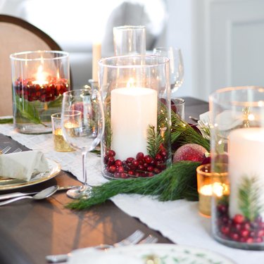 tablescape with candles in vases with pine and cranberries