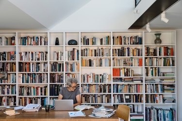 interior showing bookshelves and a person sitting near a laptop