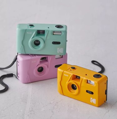 Three Kodak 35-millimeter cameras in three colors: pink, light green, and yellow