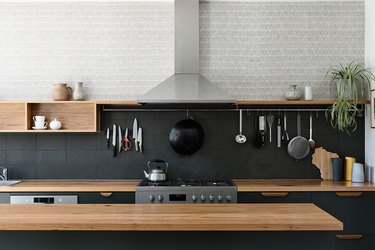 cooking area with dark backsplash and light wallpaper