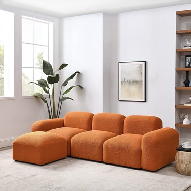 Amazon's Melpomene Convertible Modular Sectional Sherpa Sofa in orange on a beige carpet.