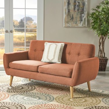Target Josephine Mid-Century Modern Petite Sofa in orange on a beige patterned carpet