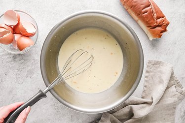 Whisking eggs, milk, and spices in a large bowl