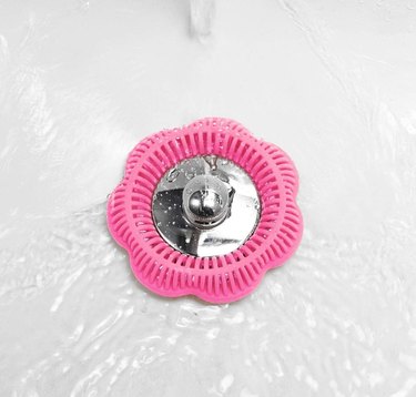 A pink hair tub ring over a bathtub drain