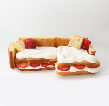 Couch made out of bread, marshmallow fluff, and strawberries on a white background.