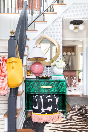 green table and fringed stool in entryway