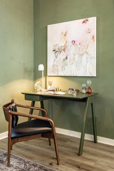 work area with green walls and leather chair with dark wood