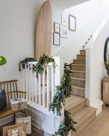 Entryway with wood surfboard and a staircase with a garland swagged over a banister
