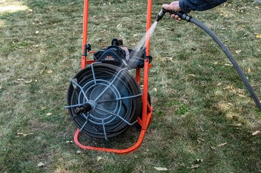 sewer drain cleaning, spraying sewer snake machine with garden hose in yard