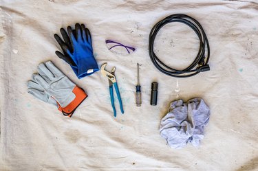 sewer drain cleaning tools and supplies on white tarp background