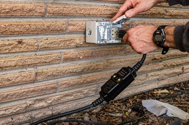 outdoor electrical outlet on brick wall, plugging in gfci cord