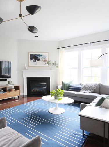 white living room with blue striped rug and modern chandelier