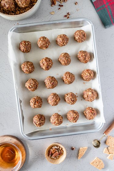 The pecan pie bourbon balls, without a chocolate coating, on an aluminum baking sheet lined with parchment paper.