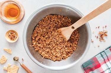 A metal bowl filled with all the ingredients on a white counter next to a green and red plaid tea towel.