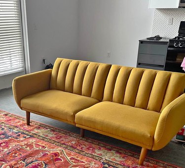 Mustard yellow sofa, red and orange rug