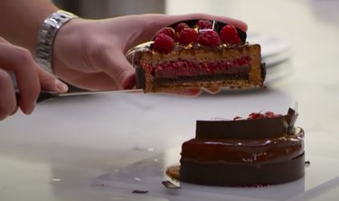 screenshot of person holding a slice of cake