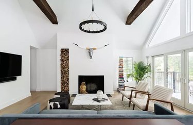 Modern living room with a floor to ceiling window, exposes beams and fireplace