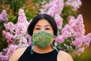 photo of Shayai Lucero wearing a green and blue mask with pink flowers in the background