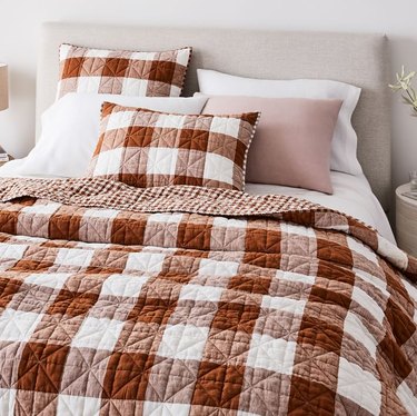 bed with red and white plaid quilt