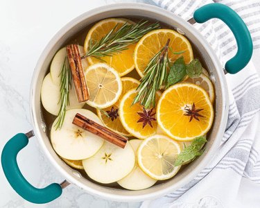 Orange slices, apple slices, cinnamon, and rosemary in a pot
