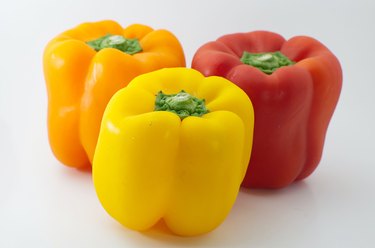 Orange, yellow, and red bell peppers on a white background