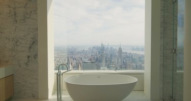 Bathtub in a penthouse facing a window overlooking New York City