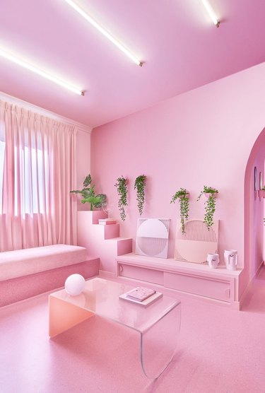 bubblegum pink living room with lucite coffee table, tubular neon lighting and pink furniture