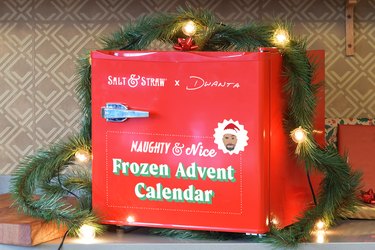 A red mini fridge that reads "Salt & Straw x Dwanta" and "Naughty and Nice Frozen Advent Calendar" with an illustration of The Rock's face on it.