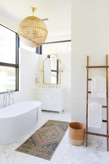 White bathroom with natural pendant light and ladder to hold towels.