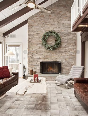 Stone clad wall around a fireplace and exposed beams in living room